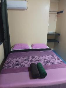 苏瓦Mishra Residence的紫色的床,上面有两条绿色毛巾