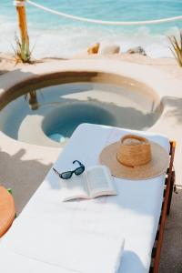 托多斯桑托斯Hotel San Cristobal Adults 15+的一张带帽子的桌子和一本书,在游泳池旁边