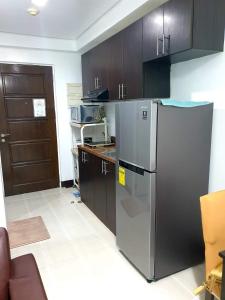 宿务Studio Unit Persimmon Condominium的厨房配有不锈钢冰箱和木制橱柜