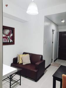 宿务Studio Unit Persimmon Condominium的客厅配有棕色沙发和桌子
