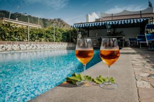 伊斯基亚Hotel Casa Giuseppina的两杯葡萄酒坐在游泳池旁