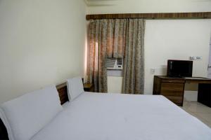 巴廷达OYO Hotel Friday's的卧室配有一张白色大床和一张书桌