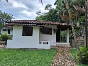 佩尼多Chalé do riacho 2的一座白色的小房子,有绿色的院子