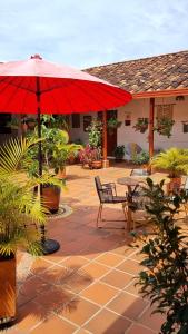 萨帕托卡La Casona Espacio Bonito的一个带桌子和红色遮阳伞的庭院
