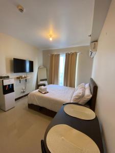 Lapu Lapu CitySeaside Serenity w/ Sunrise @ Saekyung Village One的一间卧室配有一张床、一张桌子和一台电视。