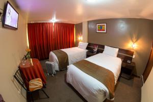 普诺UTASA VILLAREAL Inn的酒店客房设有两张床和红色窗帘