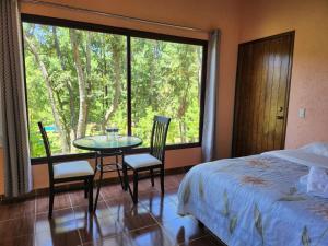 卡尔波镇Rancho San Miguel的一间卧室配有一张床、一张桌子、椅子和一扇窗户。
