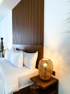 龙目岛库塔VILLA TERAUM的一张带白色枕头的床和一张带台灯的桌子
