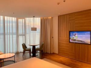下龙湾Panoramic sea homestay的配有电视和桌椅的酒店客房