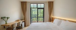 德清La Petronilla Boutique Hotel Moganshan的卧室配有白色的床和窗户。