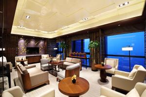 无锡无锡太湖华邑酒店的大堂配有沙发和桌子,设有大窗户。