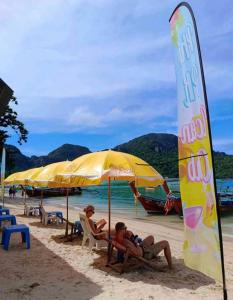 皮皮岛Phi Phi Ocean Club的两人坐在海滩上一把遮阳伞下的椅子上
