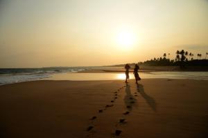 坦加拉Back of beyond - Wellness Retreat的两人在日落时分在海滩上散步