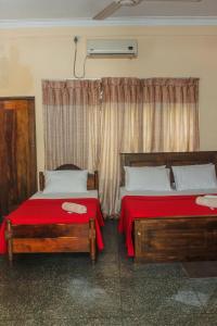 康提Spice & Herb Rooms & Food的一间卧室设有两张带红色床单的床和窗户。