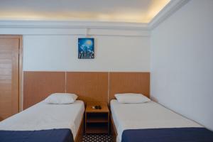 伊兹密尔Deniz Pansiyon的一间设有两张床的房间,中间设有床头柜