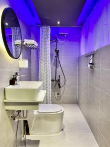 胡志明市M&H Cinema的一间带水槽、卫生间和紫色照明的浴室