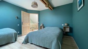 奥尔比Gîte des Pierres de Barme的一间蓝色卧室,配有两张床和一扇门