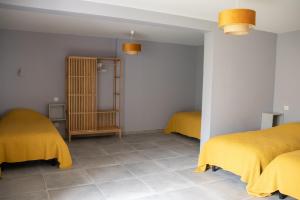 奥尔比Gîte des Pierres de Barme的宿舍间的两张床,上面有黄色的毯子