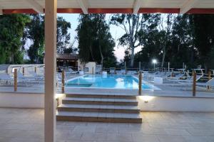 普罗斯西托角Giardini Sausari Residence的一个带白色椅子和桌子的游泳池