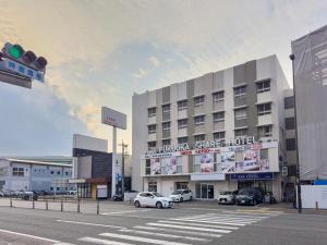 福冈Fukuoka Share Hotel的停车场内停放汽车的大型建筑