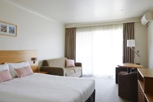 拜伦湾海湾汽车旅馆的配有一张床和一把椅子的酒店客房