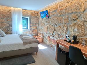 帕科斯费雷拉Agrafonte的一间卧室设有石墙、一张床和一张书桌