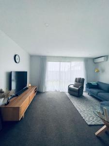 奥克兰Stylish Industrial Holiday House in Pakuranga Free Wifi Netflix的一间带电视和沙发的客厅