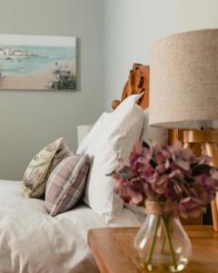 塞拉戴克Sea Sound的一张带枕头的床和一张带台灯的桌子