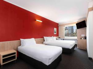 悉尼悉尼达令港宜必思酒店的酒店客房设有两张床和红色的墙壁。