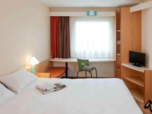 柏林柏林波茨坦广场宜必思酒店的一间酒店客房,配有一张白色的床和一张书桌