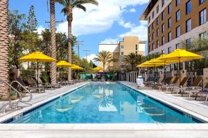 安纳海姆Home2 Suites By Hilton Anaheim Resort的一个带椅子和遮阳伞的游泳池
