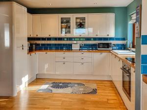 GelstonCeardach的厨房配有白色橱柜和蓝色瓷砖