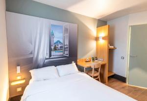 里摩日B&B HOTEL Limoges 1的卧室配有白色的床、书桌和窗户。