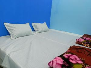 乌贾因M Baba Guest House的一张带两个枕头和毯子的大型白色床