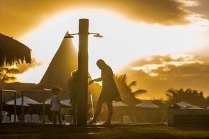 瓜拉久巴Vila Galé Resort Marés - All Inclusive的日落时站在十字架旁的女人