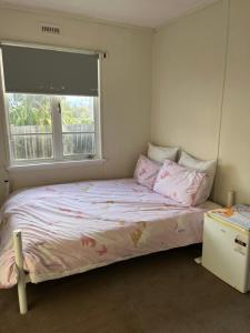 WarraneJennifer的一间卧室配有一张带粉色床单的床和一扇窗户。