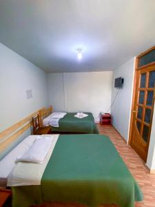 瓦拉斯Chacraraju Hostel的一间设有两张床和电视的房间