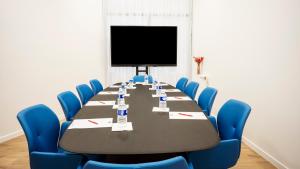 巴涅奥莱Séjours & Affaires Paris Bagnolet的一间会议室,配有长桌子和蓝色椅子