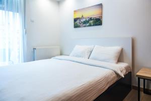 诺维萨德Daisy resort的卧室配有一张白色床,墙上挂着一幅画