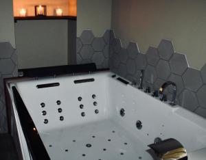MarlhesSuperbe appartement avec jacuzzi et jardin privé的带浴缸和水槽的浴室