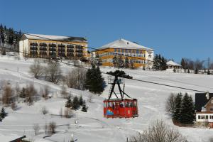 奥泊维森塔尔奥泊维森塔尔全景酒店的雪上人乘坐的红色滑雪缆车