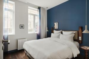 里尔Edgar Suites Lille - Faidherbe的卧室配有白色大床和蓝色的墙壁