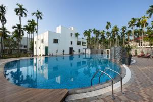 希莫加Malnad Shire Eco Resort的棕榈树建筑前的游泳池
