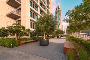迪拜BURJ ROYAL-Luxurious 2 Bedrooms -DOWNTOWN-Burj & Fountain View的建筑前有长椅和树木的公园