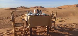 AdrouineNomads Luxury Camp Merzouga的沙漠中的一张桌子和椅子