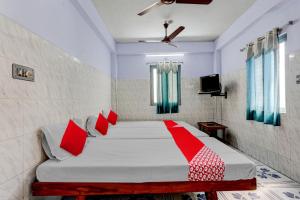 蒂鲁帕蒂OYO Flagship Sai Ganesh Deluxe Lodge的一间卧室配有红色枕头的床