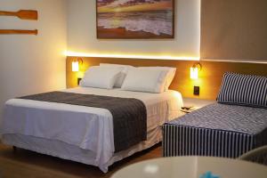 马拉戈日O Azul de Maragogi - Pousada Premium的酒店客房设有一张大床和一张沙发。