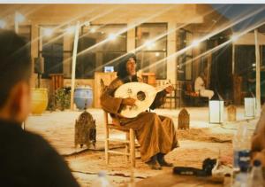 Aït DaoudThe Original Camp的坐在椅子上,拿着吉他的人