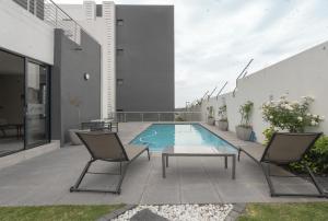 米德兰Tranquil Zen Oasis in Midrand: The Perfect Retreat的庭院设有游泳池、两把椅子和一张桌子