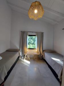 拉安戈斯图拉镇Al pie del Cerro的客房设有两张床、一个窗户和一个吊灯。